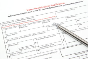 A United States voter registration application ready to be filled out with a silver pen.