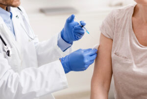 Vaccination programme. Doctor with syringe making injection for old patients, close up